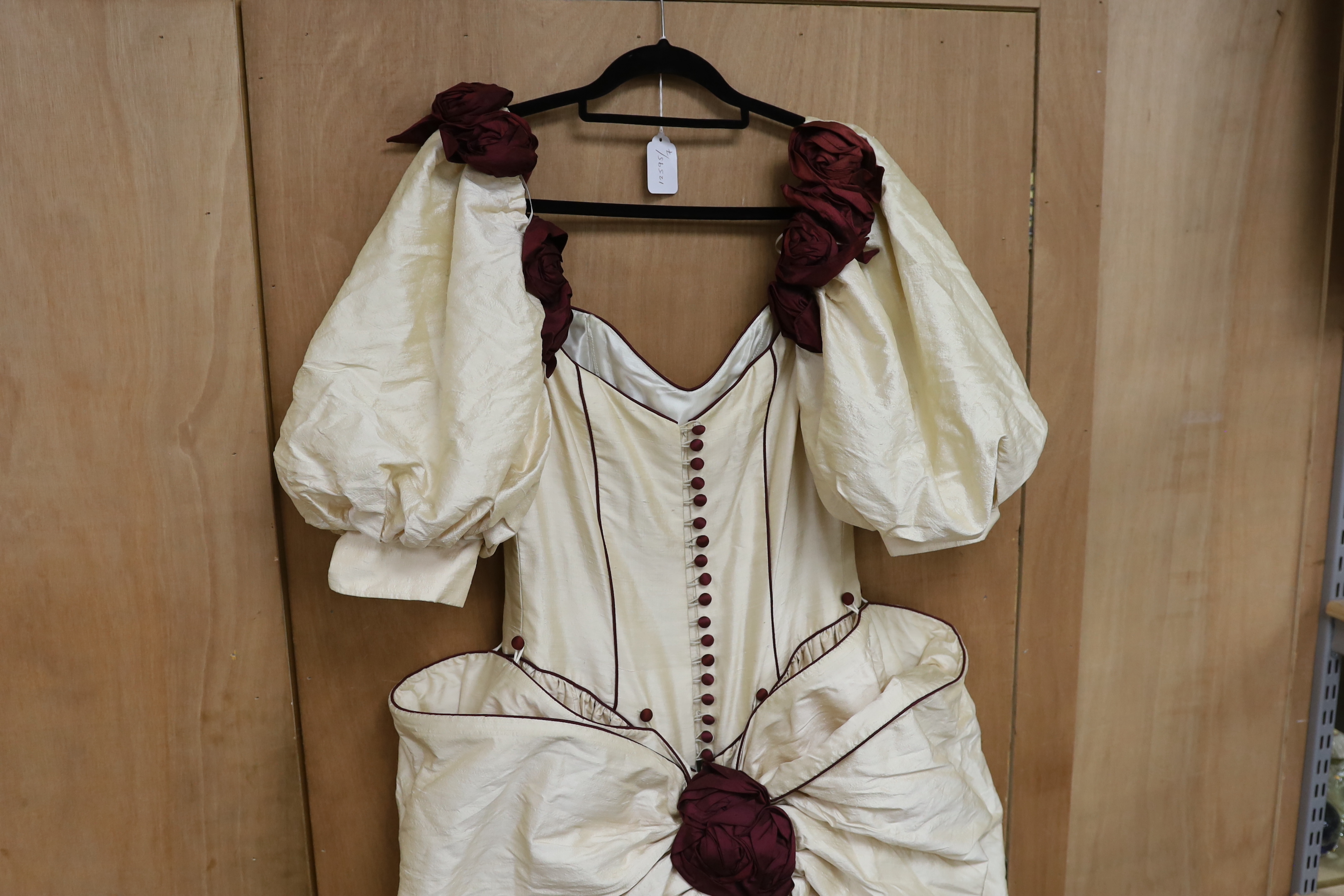 A late 20th century cream silk and burgundy trimmed gown, with bustle, possibly operatic or theatrical